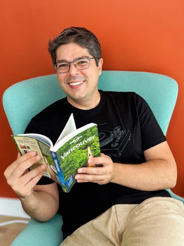 Adriano Carlos em Vancouver, sentado com um livro sobre a cidade