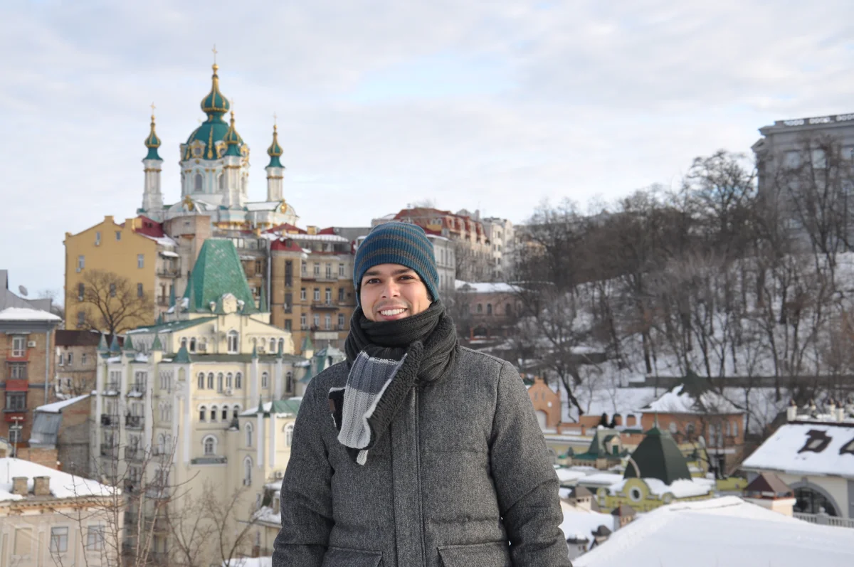 Adriano Carlos na Ucrânia, com construções históricas e neve ao fundo